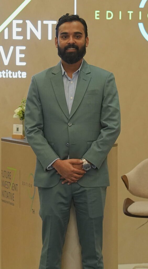 Man in a sage green suit standing in front of a Future Investment Initiative 9th Edition backdrop